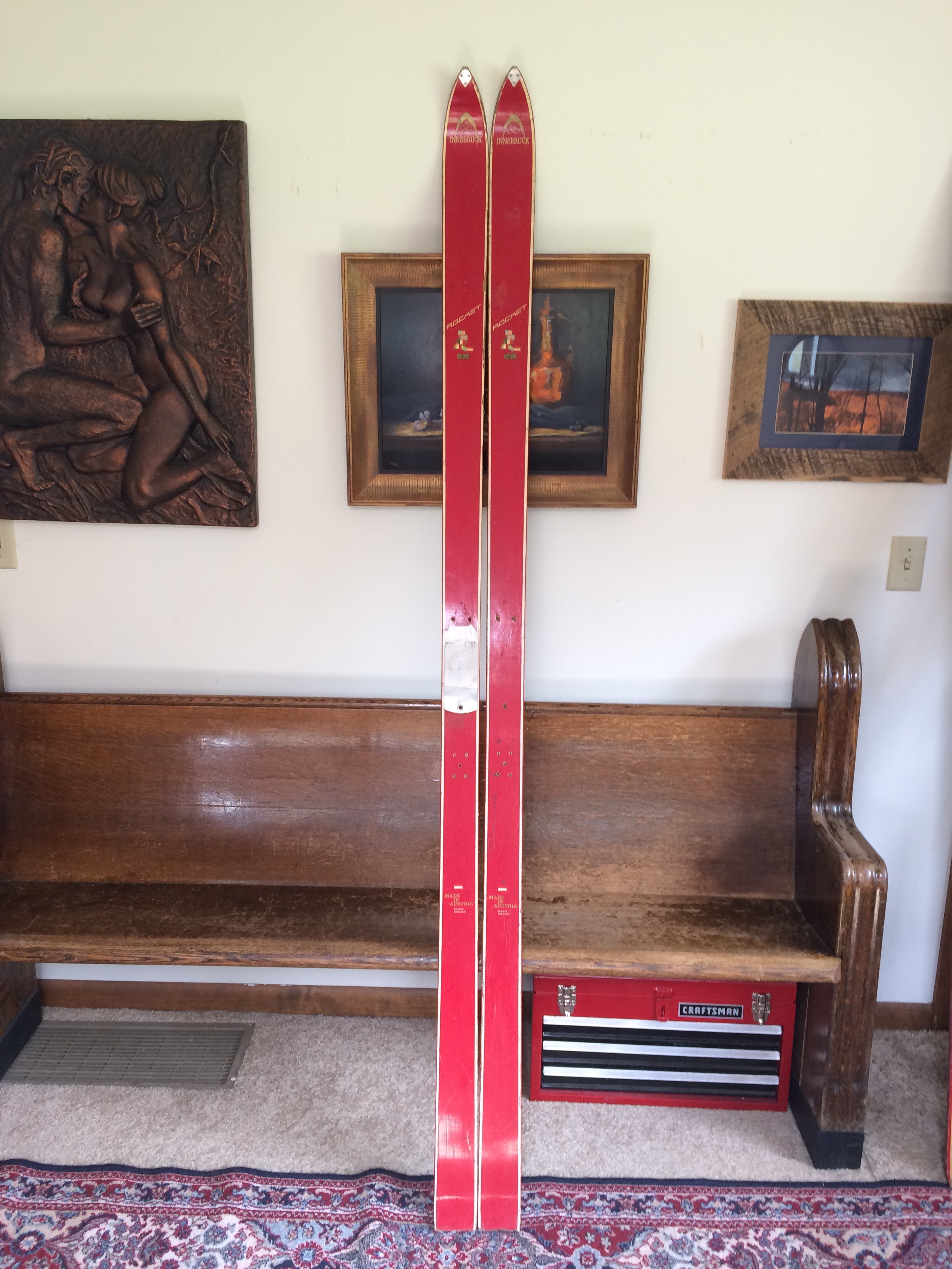 The Innsbruck ROCKET snow skis red full-length top sheet view leaning on wooden bench | LongSkisTruck